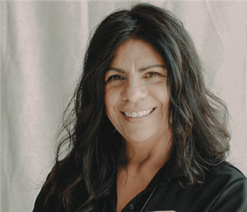 Woman with black hair standing in front of white background