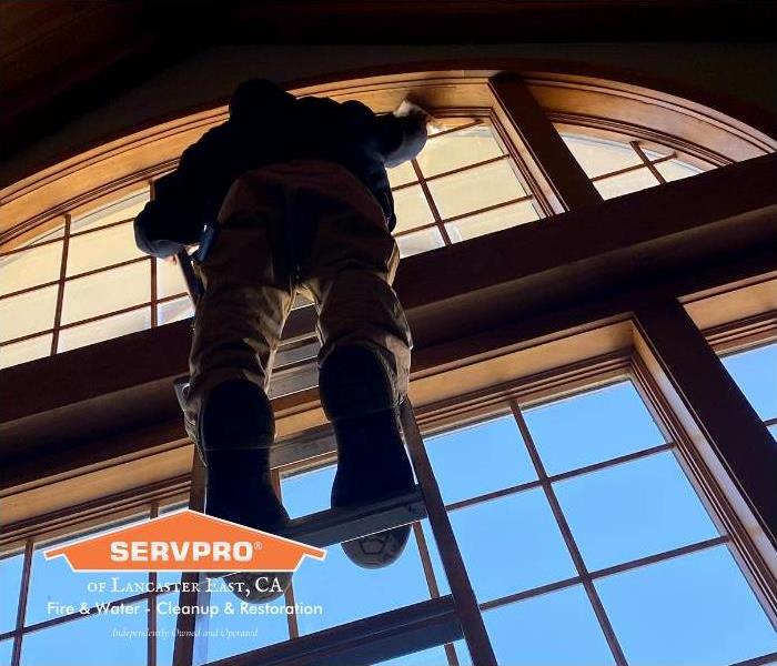 man on ladder cleaning commercial window