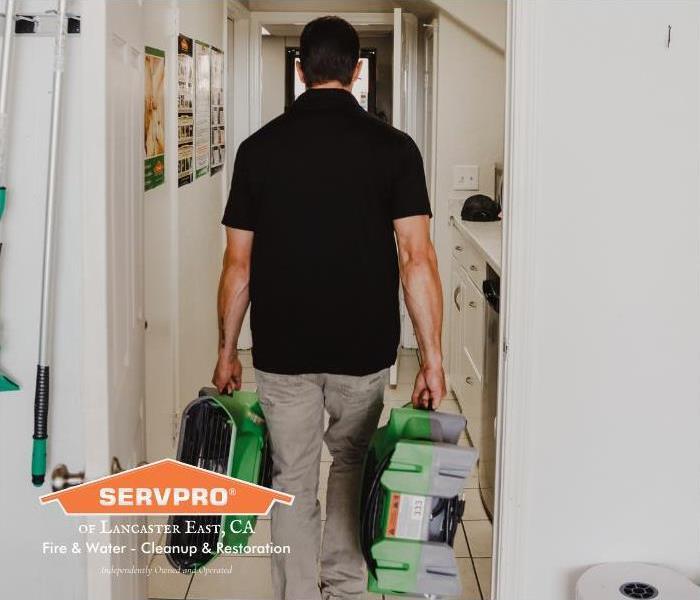 man carrying green equipment down office hallway